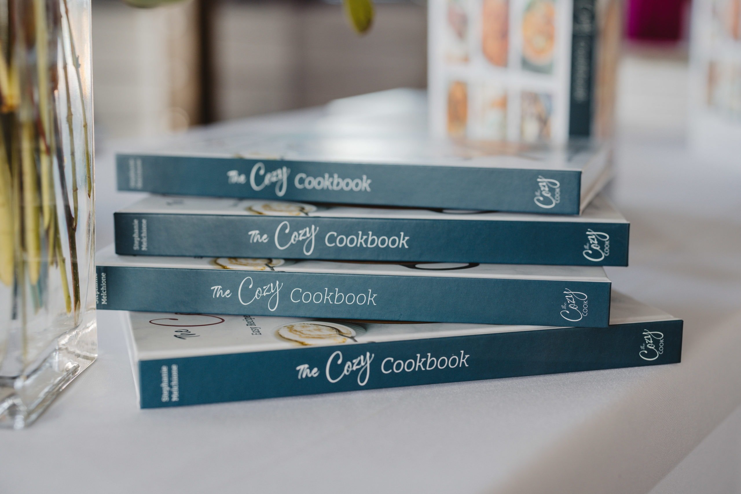 A stack of The Cozy Cookbook on a white table.