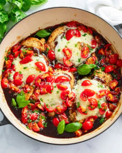 Bruschetta Chicken in a skillet with Balsamic sauce, diced tomatoes, and basil.