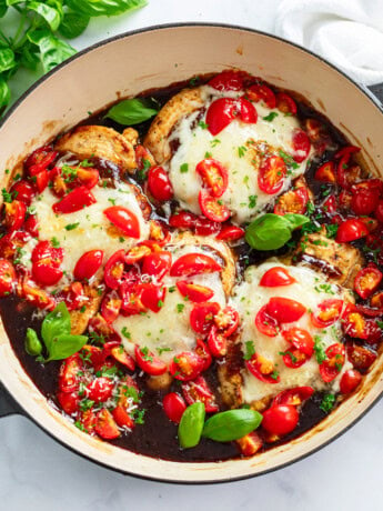 Bruschetta Chicken in a skillet with Balsamic sauce, diced tomatoes, and basil.