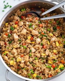 A skillet filled with Chicken Fried Rice with spoons in it.