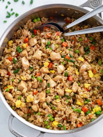 A skillet filled with Chicken Fried Rice with spoons in it.