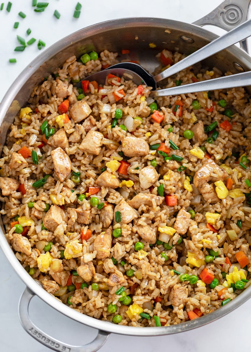 A skillet filled with Chicken Fried Rice with spoons in it.