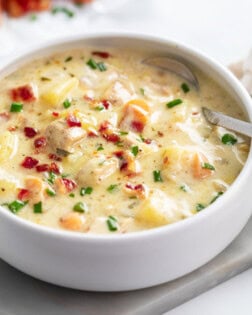 Chicken Potato Soup in a white bowl with bacon and chives on top.