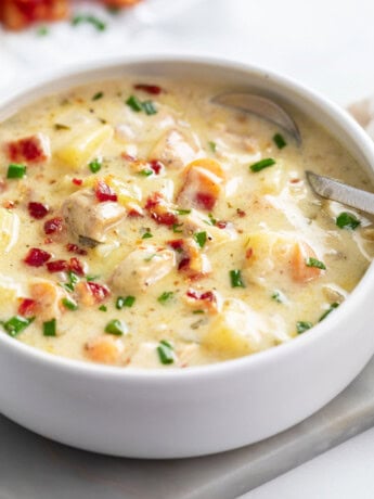 Chicken Potato Soup in a white bowl with bacon and chives on top.