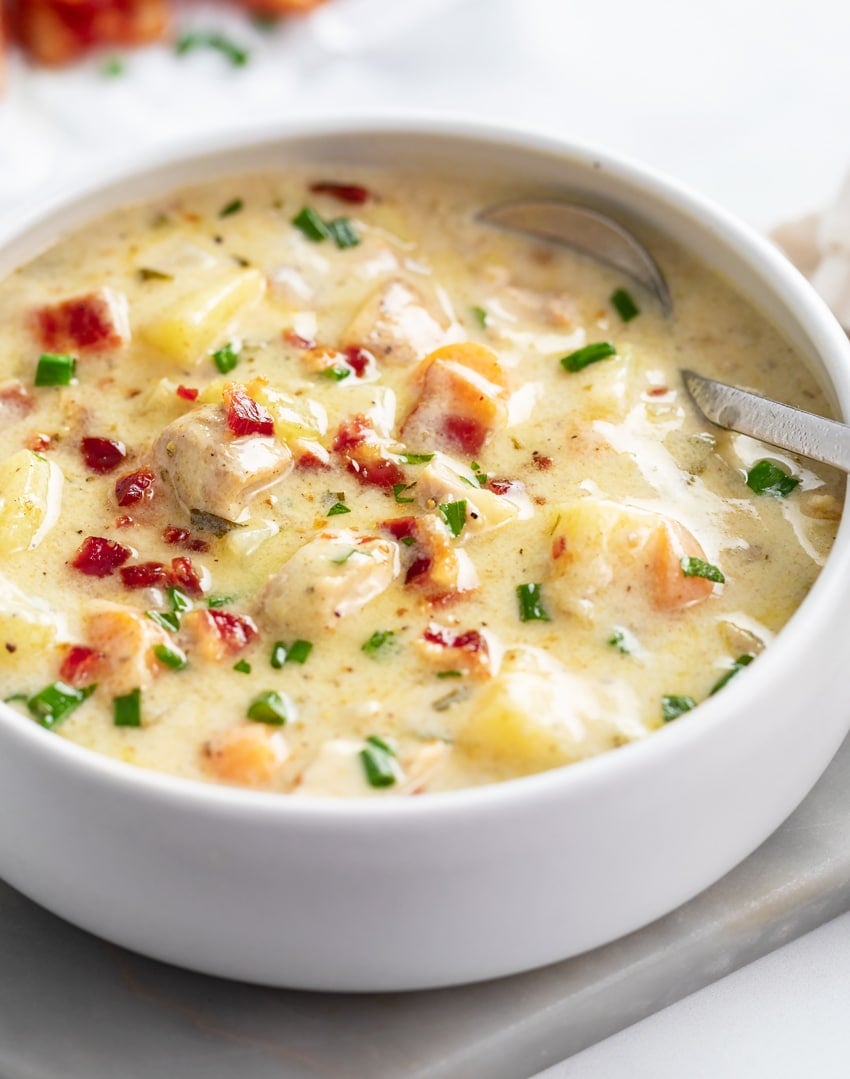 Chicken Potato Soup in a white bowl with bacon and chives on top.