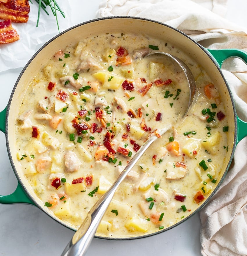 A soup pot filled with Creamy Chicken Potato Soup with bacon and chives on top.