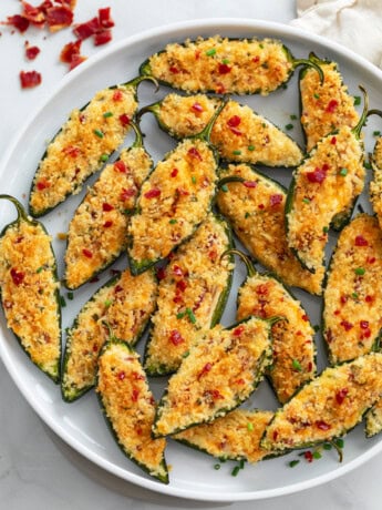 A plate of Jalapeno Poppers with chives and bacon on top.