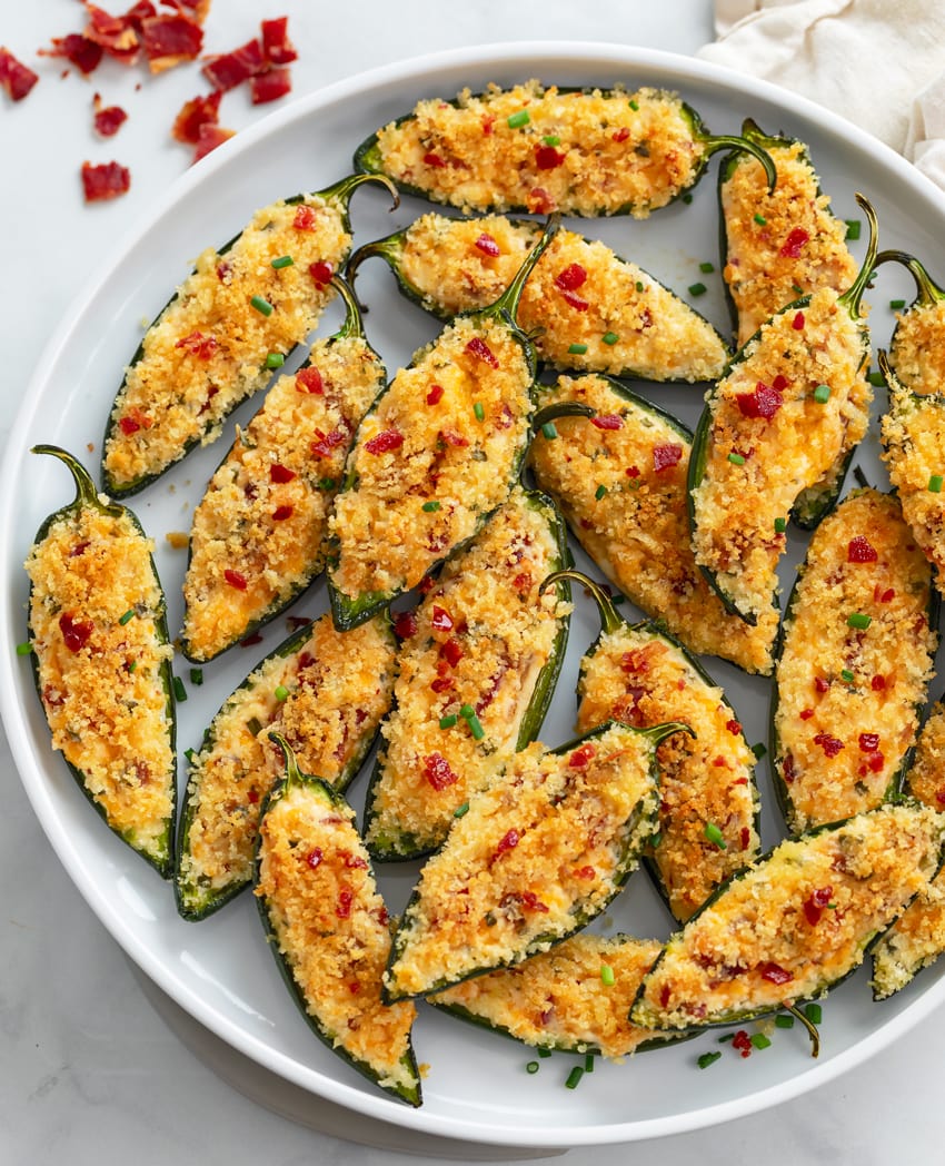 A plate of Jalapeno Poppers with chives and bacon on top.