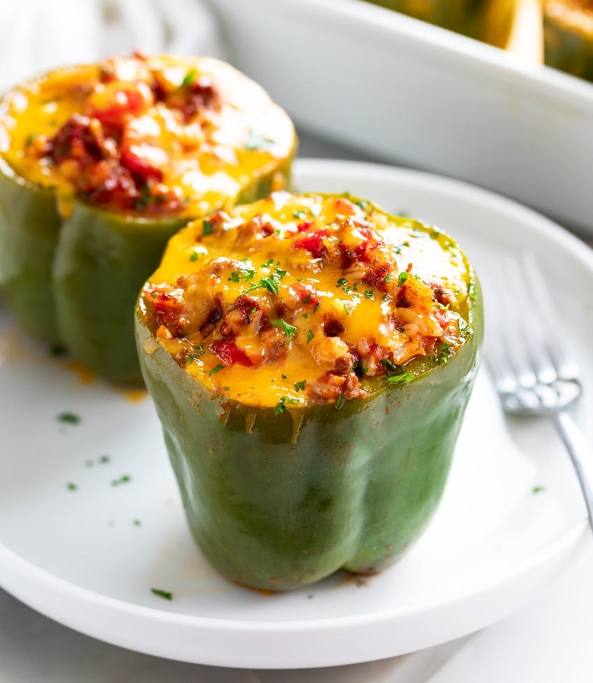 Stuffed Peppers on a white plate with melted cheese on top.