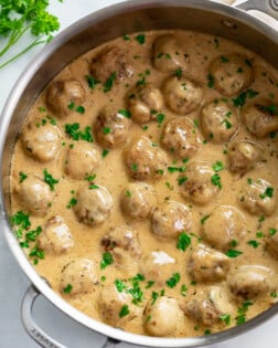 Swedish Meatballs in a skillet with a gravy cream sauce and fresh parsley.