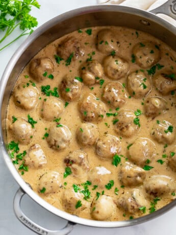 Swedish Meatballs in a skillet with a gravy cream sauce and fresh parsley.