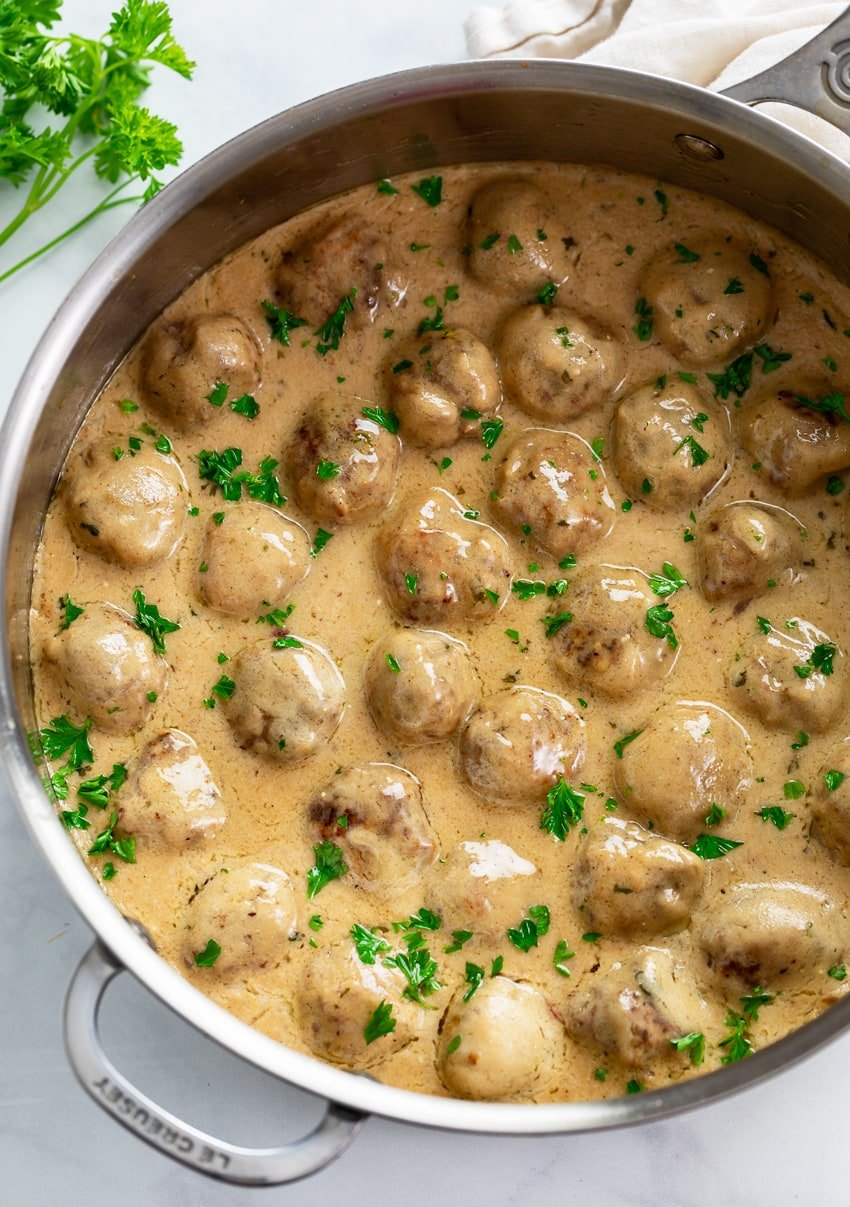 Swedish Meatballs in a skillet with a gravy cream sauce and fresh parsley.