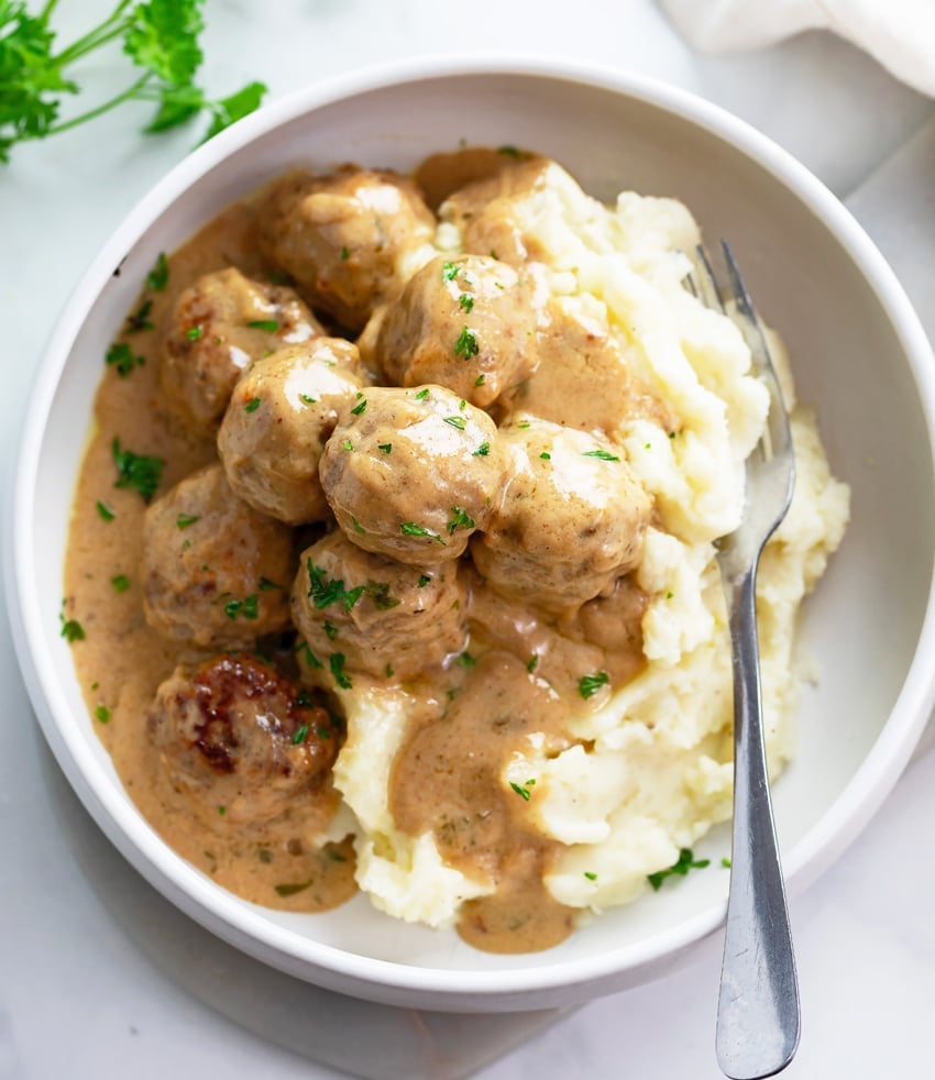 A plate with Swedish Meatballs and a gravy cream sauce over mashed potatoes. 