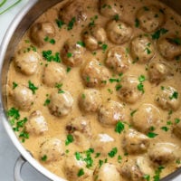 A skillet filled with Swedish Meatballs in a gravy cream sauce with fresh parsley.