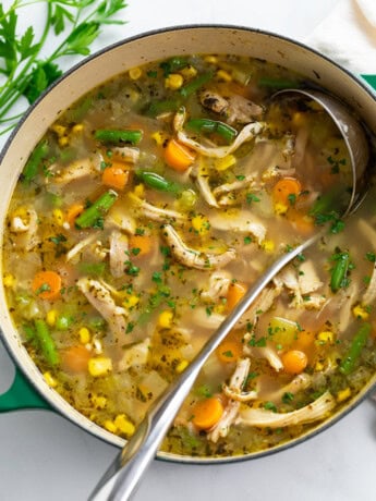 Chicken Vegetable Soup in a green soup pot with a ladle.