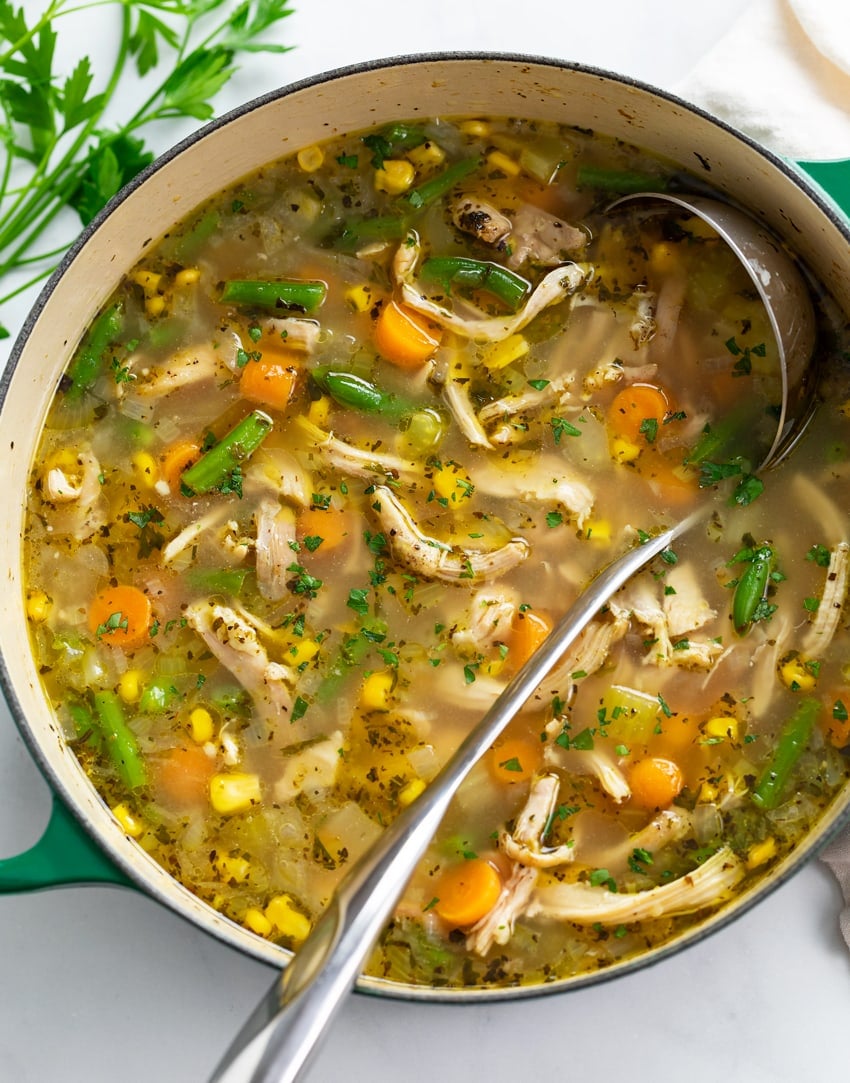 Chicken Vegetable Soup in a green soup pot with a ladle.