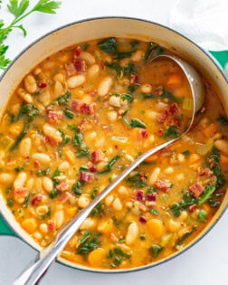 A soup pot with White Bean Soup with a ladle.