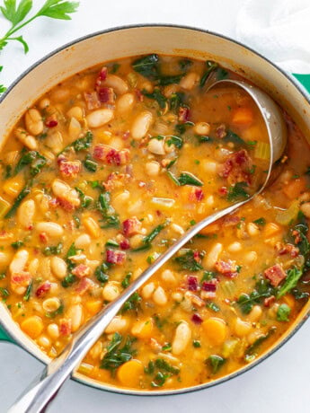 A soup pot with White Bean Soup with a ladle.