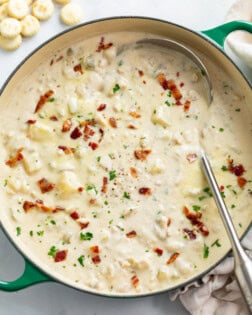 A soup pot filled with Clam Chowder with bacon and parsley on top.