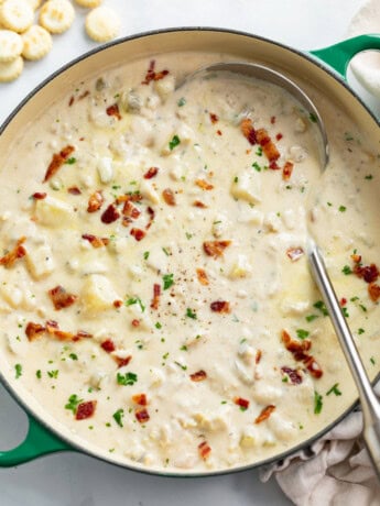 A soup pot filled with Clam Chowder with bacon and parsley on top.