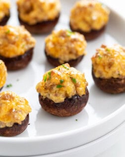 A white plate with Sausage Stuffed Mushrooms on it.