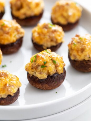 A white plate with Sausage Stuffed Mushrooms on it.