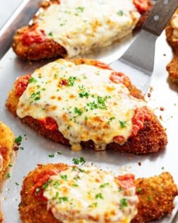 A spatula lifting up a piece of chicken parmesan.