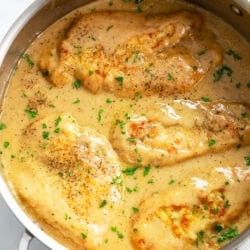 A skillet filled with Chicken and Gravy with fresh parsley on top.