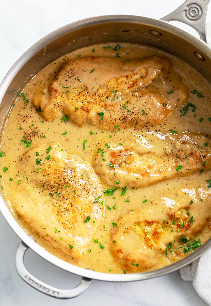 A skillet filled with Chicken and Gravy with fresh parsley on top.