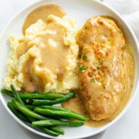 Chicken and Gravy on a white plate with green beans.