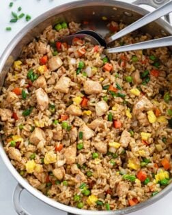 A skillet of Chicken Fried Rice with spoons in it.