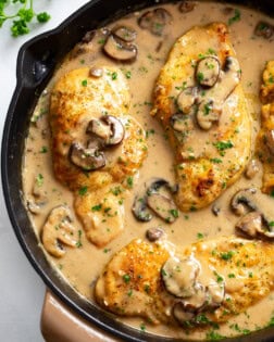 Chicken Marsala in a skillet with marsala sauce, mushrooms, and parsley.