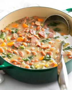 Ham Soup in a green Dutch oven with a metal ladle.