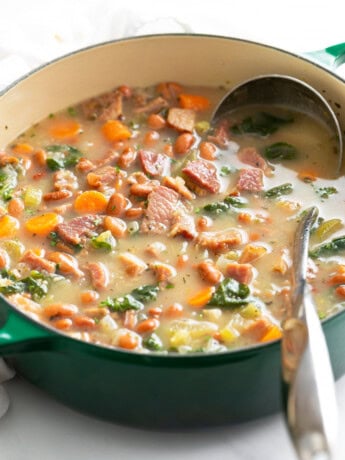 Ham Soup in a green Dutch oven with a metal ladle.