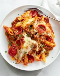 A white plate of Pizza Pasta with Pepperoni and meat sauce.