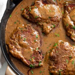 Steak with Gravy in a skillet with parsley on top.