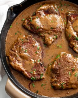 Steak with Gravy in a skillet with parsley on top.