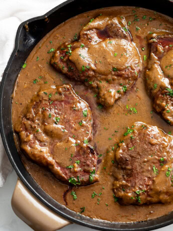 Steak with Gravy in a skillet with parsley on top.