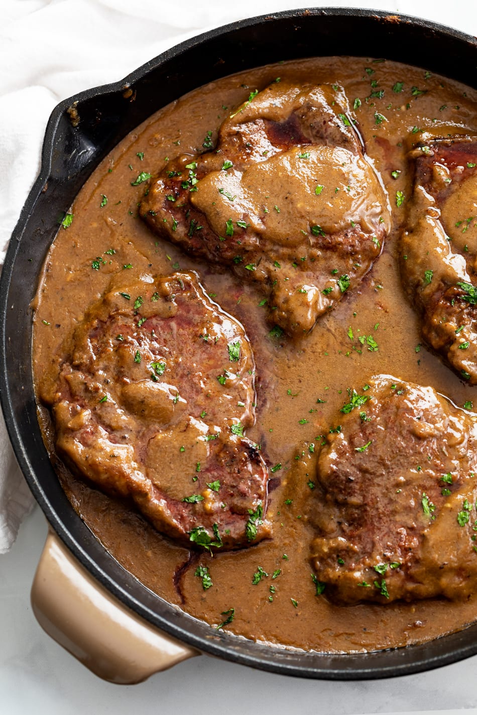 Steak with Gravy in a skillet with parsley on top.