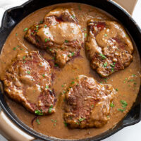A skillet filled with Steak and Gravy with parsley on top.