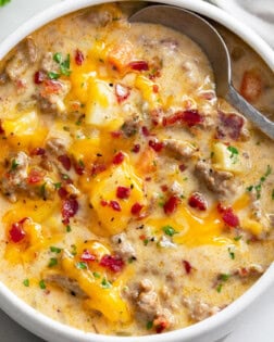 A bowl of Cheeseburger Soup with bacon on top and a spoon on the side.