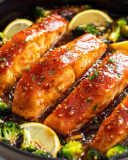 Honey Glazed Salmon in a skillet with broccoli and lemon wedges.