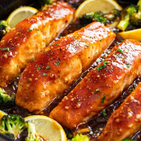 Honey Glazed Salmon in a skillet with broccoli and lemon wedges.