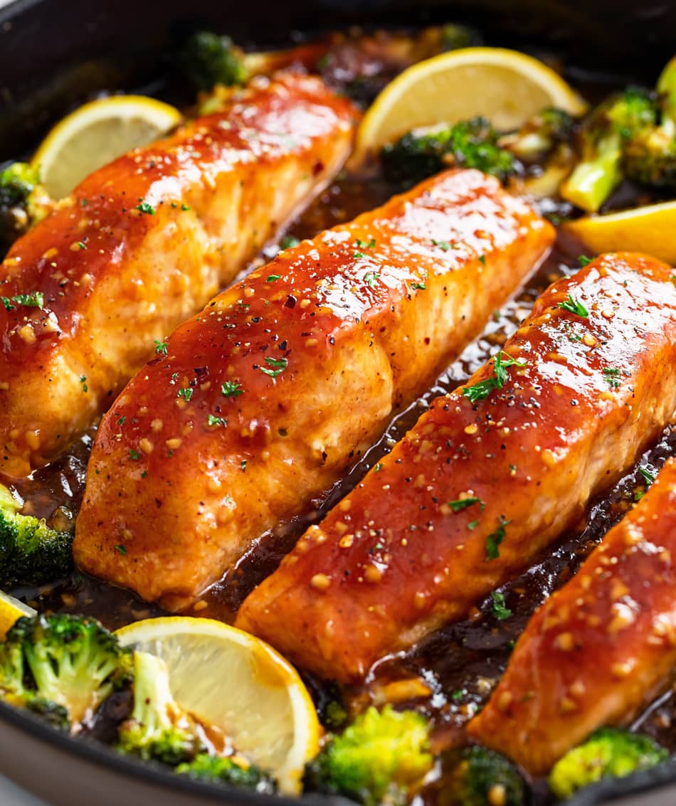 Honey Glazed Salmon in a skillet with broccoli and lemon wedges.