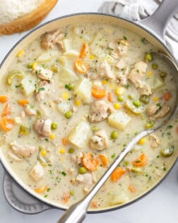 A soup pot filled with Creamy Chicken Soup with a ladle on the side.