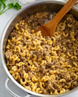 A skillet of homemade Hamburger Helper with a wooden spoon.