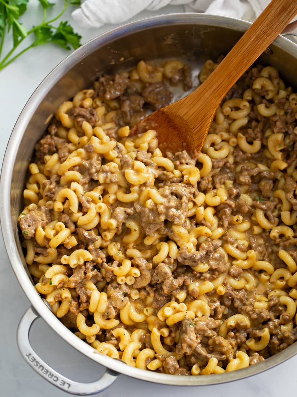A skillet of homemade Hamburger Helper with a wooden spoon.