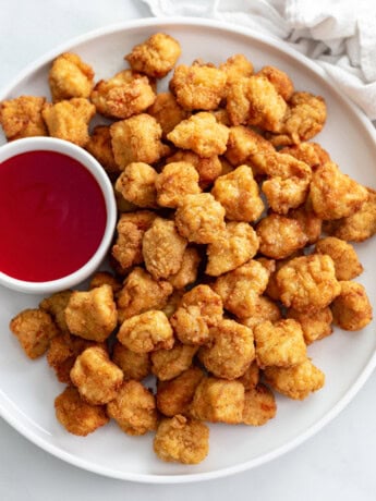 Popcorn Chicken on a white plate with sweet and sour sauce.