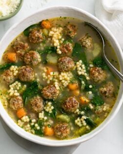 Italian Wedding Soup in a white bowl with a spoon.