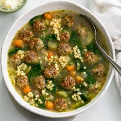 Italian Wedding Soup in a white bowl with meatballs, spinach, and acini de pepe.